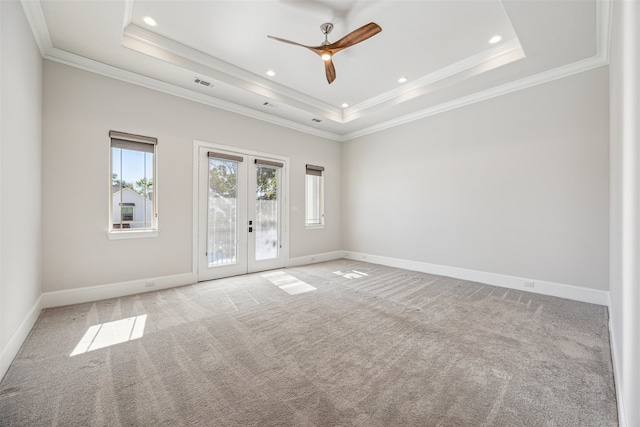 carpeted spare room featuring french doors, a raised ceiling, ceiling fan, and crown molding