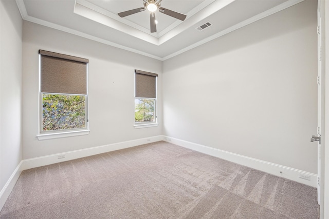 empty room featuring carpet flooring, a tray ceiling, ceiling fan, and crown molding