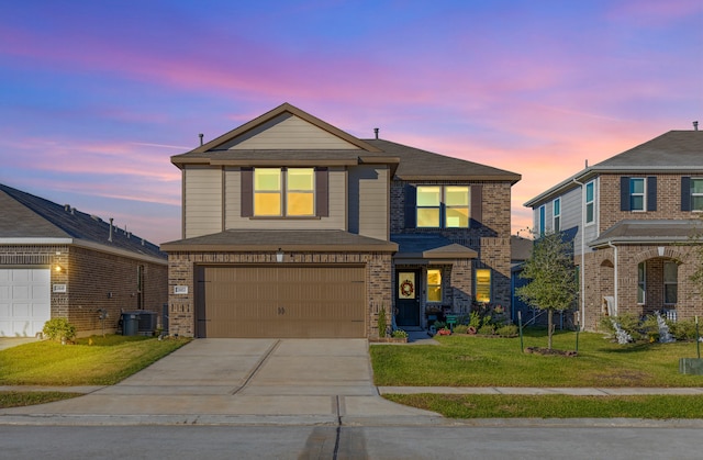 view of front of home with a garage, a lawn, and central AC