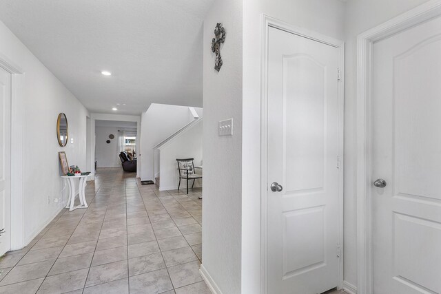 corridor featuring light tile patterned floors and a textured ceiling