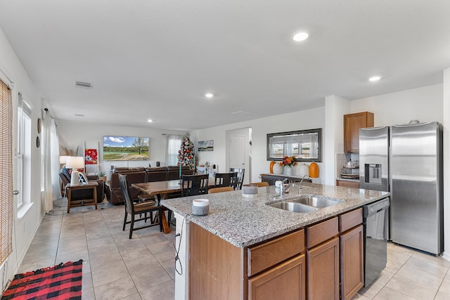 kitchen with dishwasher, sink, light tile patterned floors, an island with sink, and stainless steel fridge with ice dispenser