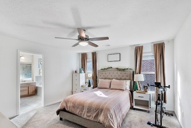 bedroom with ceiling fan, ensuite bathroom, light carpet, and multiple windows