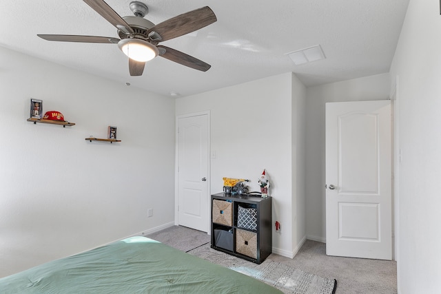 bedroom featuring ceiling fan, light carpet, and a textured ceiling