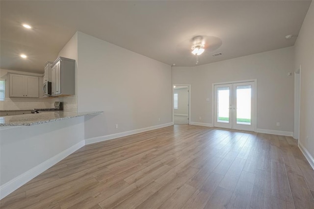 unfurnished living room with french doors, light hardwood / wood-style floors, and ceiling fan