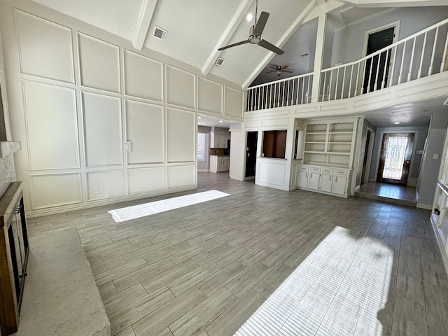 unfurnished living room featuring beam ceiling, ceiling fan, and high vaulted ceiling