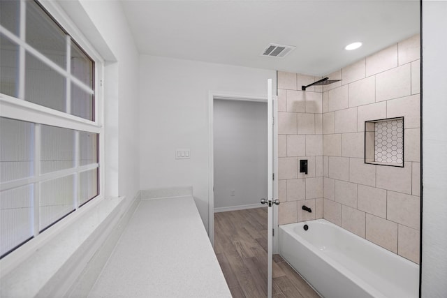 bathroom featuring wood-type flooring and tiled shower / bath combo