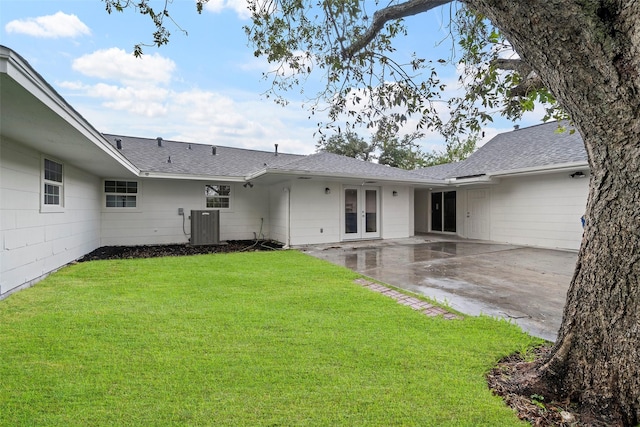 rear view of house featuring french doors, central AC, a patio area, and a lawn