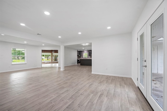 unfurnished living room featuring french doors and light hardwood / wood-style floors