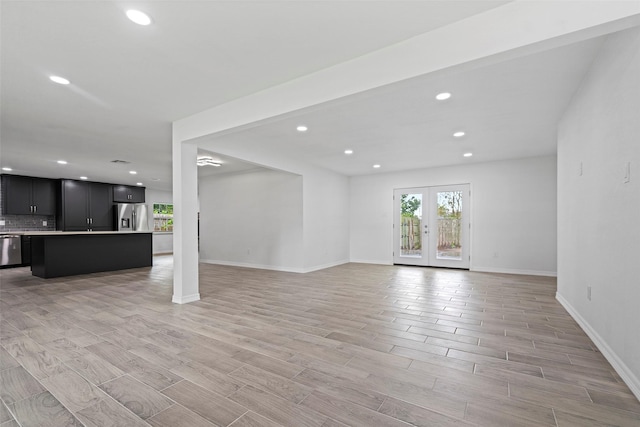 unfurnished living room with light wood-type flooring and french doors