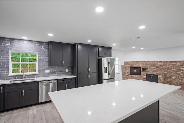 kitchen featuring sink, a kitchen island, stainless steel appliances, and light hardwood / wood-style flooring