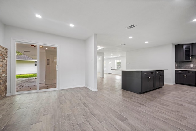 kitchen featuring a center island, light wood-type flooring, and backsplash