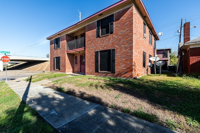 view of front of home featuring a balcony and a front yard