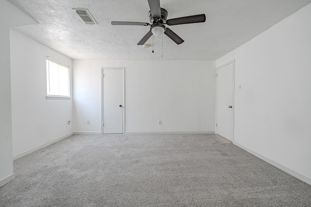 carpeted spare room featuring a textured ceiling and ceiling fan