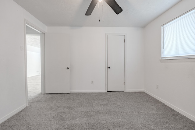 unfurnished bedroom featuring a textured ceiling, ceiling fan, and light carpet