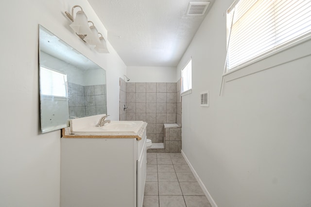 bathroom with vanity, tile patterned flooring, toilet, a textured ceiling, and a tile shower