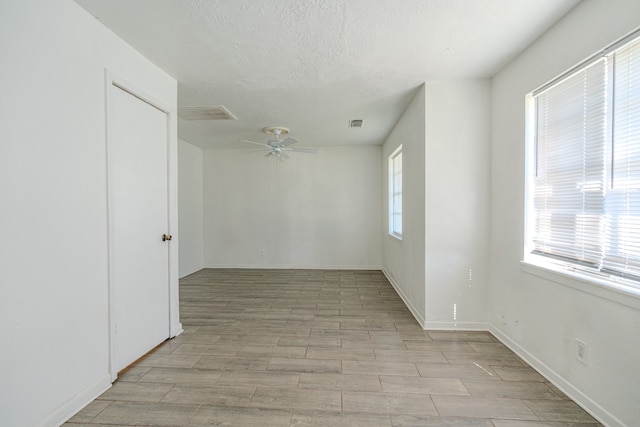 spare room featuring a textured ceiling, light hardwood / wood-style floors, and ceiling fan