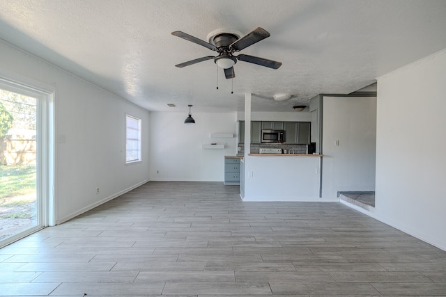 unfurnished living room with a textured ceiling, a wealth of natural light, and light hardwood / wood-style flooring