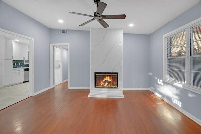 unfurnished living room with ceiling fan, light wood-type flooring, and a fireplace