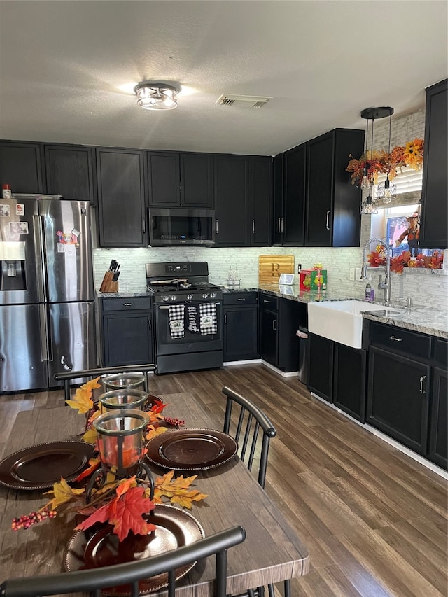 kitchen featuring dark hardwood / wood-style floors, light stone countertops, sink, and appliances with stainless steel finishes