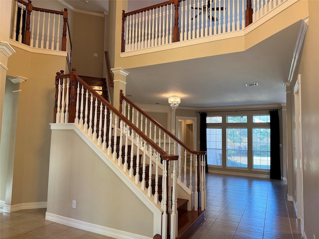 stairs featuring tile patterned floors, ornamental molding, and a towering ceiling