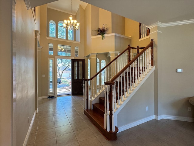 tiled entrance foyer with ornate columns, crown molding, a high ceiling, and a chandelier