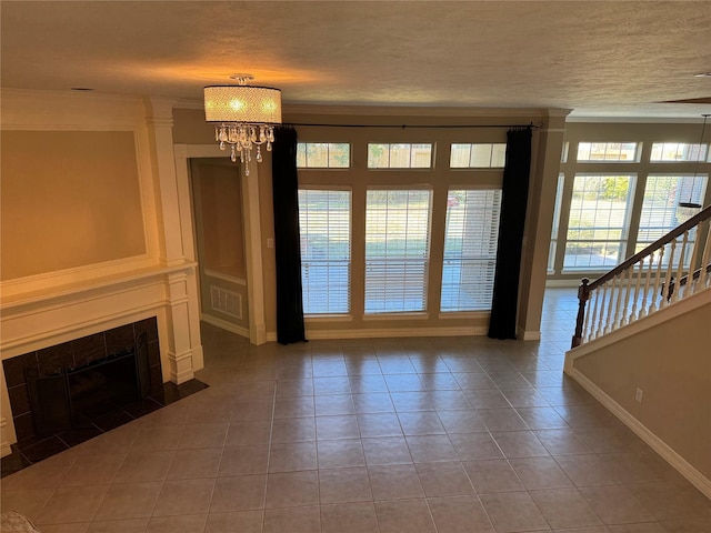 unfurnished living room with ornamental molding, tile patterned flooring, a tile fireplace, and a notable chandelier