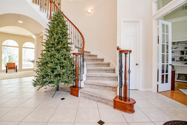 stairs featuring french doors, a towering ceiling, and tile patterned floors