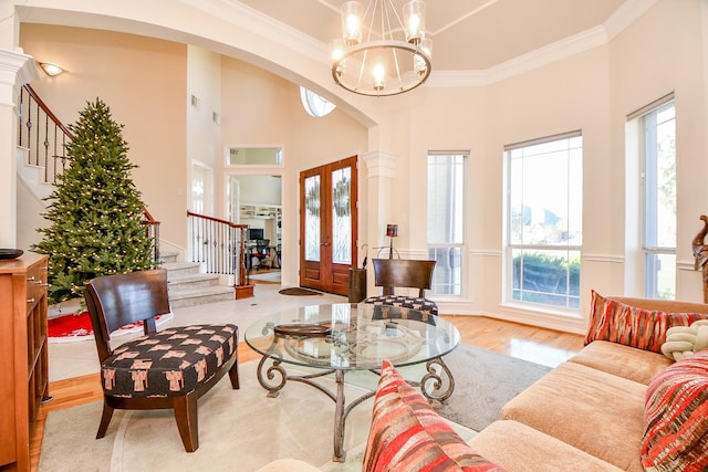 living room featuring ornamental molding, french doors, a healthy amount of sunlight, and a notable chandelier