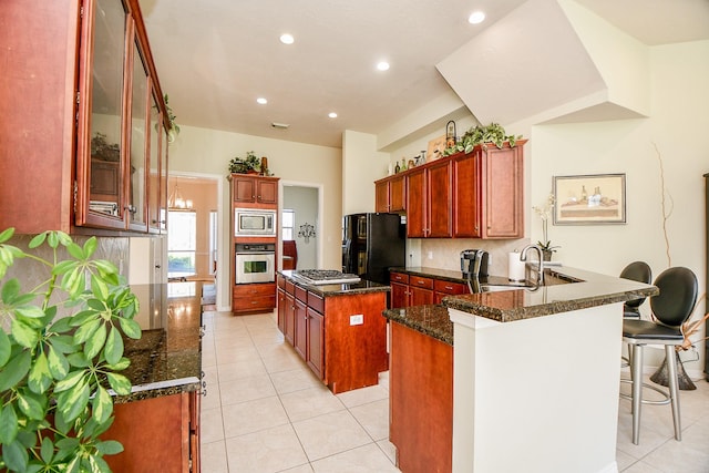 kitchen with sink, light tile patterned flooring, a breakfast bar, a kitchen island, and appliances with stainless steel finishes