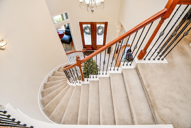 stairway with a chandelier and french doors