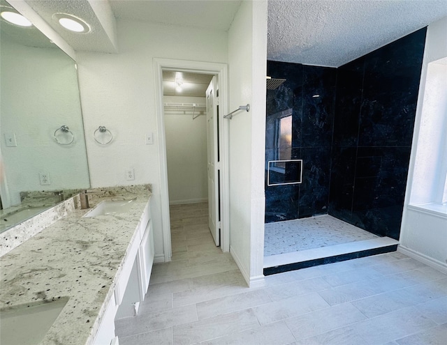 bathroom with tiled shower, a textured ceiling, and vanity