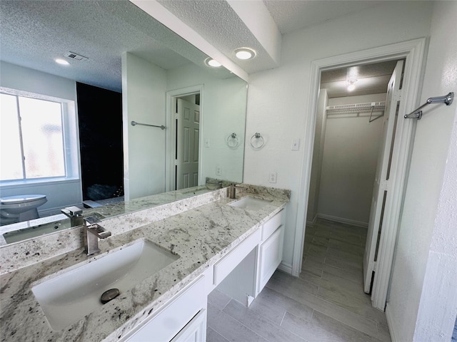 bathroom featuring hardwood / wood-style floors, vanity, a textured ceiling, and toilet