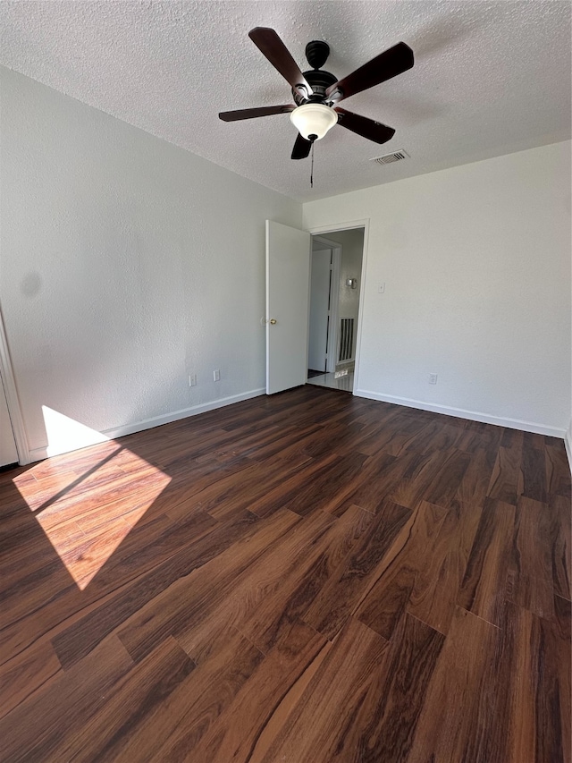 empty room featuring a textured ceiling, dark hardwood / wood-style floors, and ceiling fan