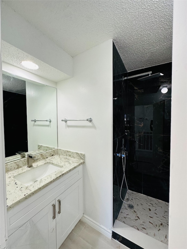 bathroom featuring vanity, a textured ceiling, and tiled shower