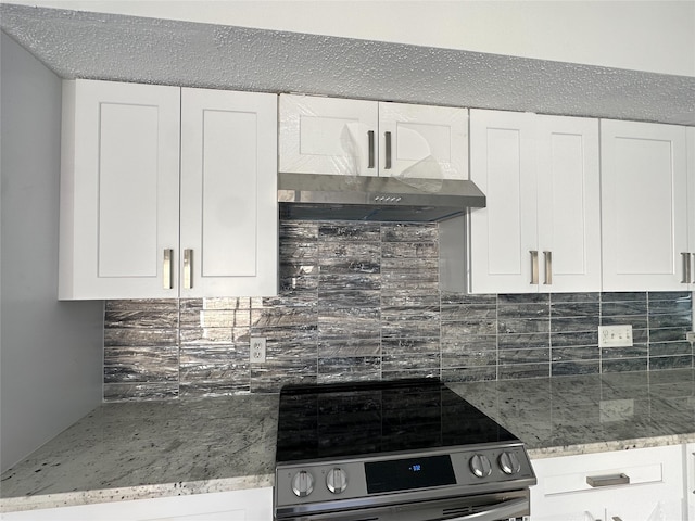 kitchen with white cabinets, stove, light stone countertops, and backsplash