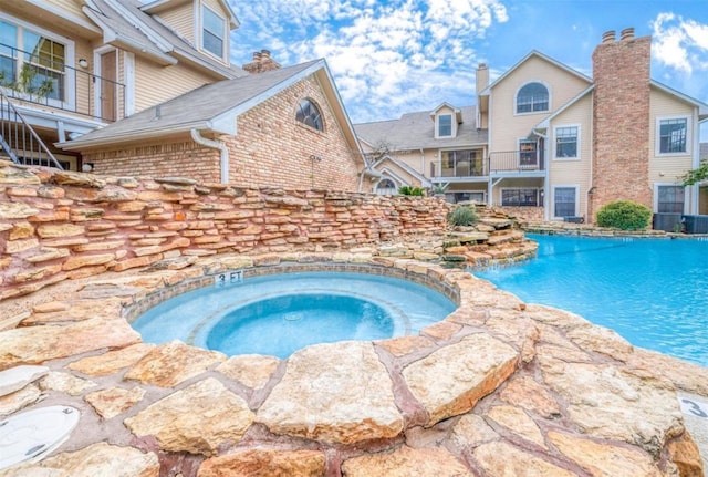 view of swimming pool with an in ground hot tub and pool water feature