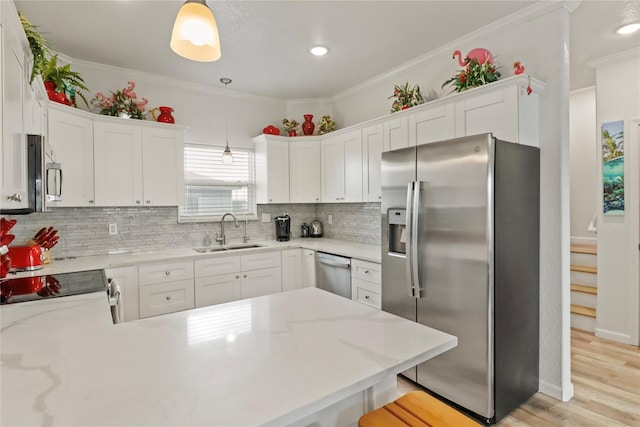 kitchen featuring appliances with stainless steel finishes, white cabinetry, hanging light fixtures, and sink