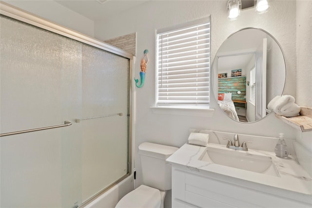 full bathroom with vanity, bath / shower combo with glass door, and toilet