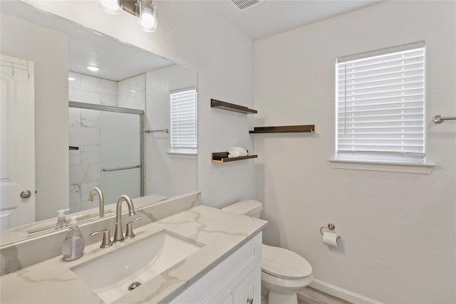 bathroom featuring vanity, toilet, and a shower with shower door