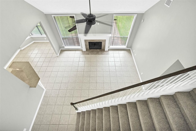 unfurnished living room with tile patterned flooring, ceiling fan, a healthy amount of sunlight, and a tile fireplace