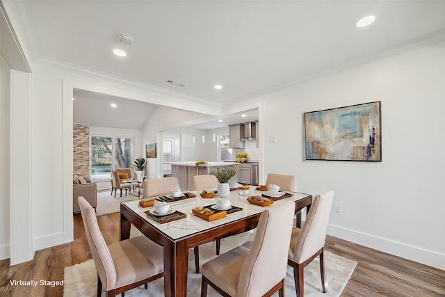 dining space with lofted ceiling, light wood-type flooring, and ornamental molding