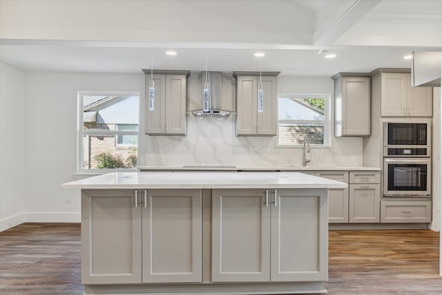 kitchen featuring hardwood / wood-style floors, wall chimney exhaust hood, gray cabinets, and beamed ceiling