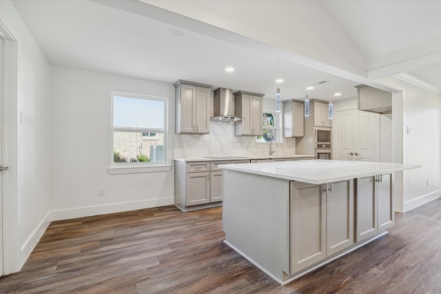 kitchen featuring gray cabinetry, wall chimney exhaust hood, dark hardwood / wood-style flooring, a kitchen island, and appliances with stainless steel finishes