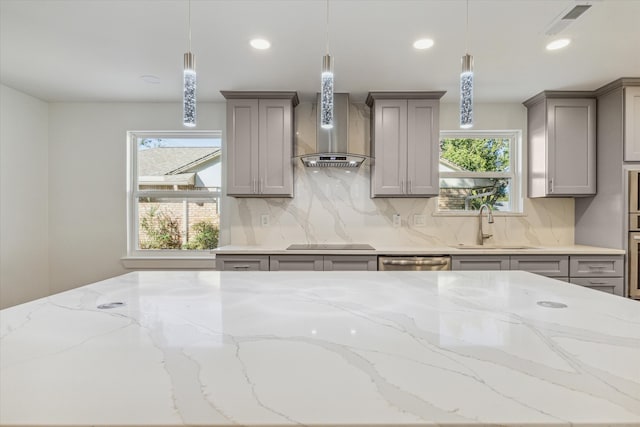 kitchen with stainless steel appliances, plenty of natural light, hanging light fixtures, and wall chimney range hood