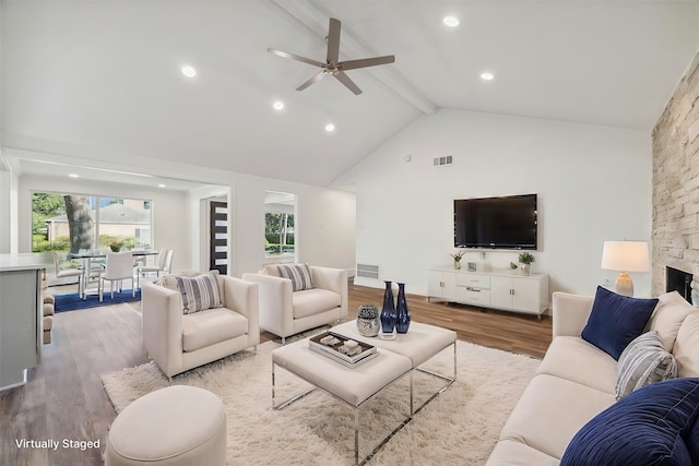 living room featuring beamed ceiling, light wood-type flooring, a wealth of natural light, and ceiling fan