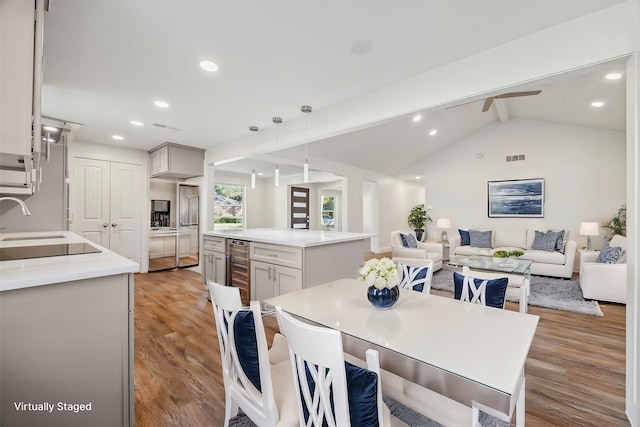 dining space featuring vaulted ceiling with beams, ceiling fan, light hardwood / wood-style floors, and wine cooler