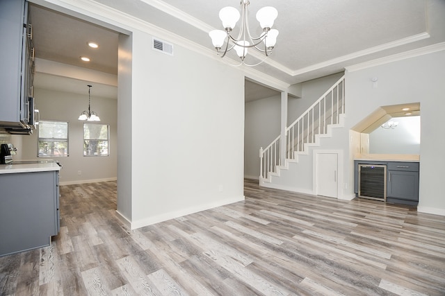 unfurnished living room featuring light wood-type flooring, an inviting chandelier, and ornamental molding