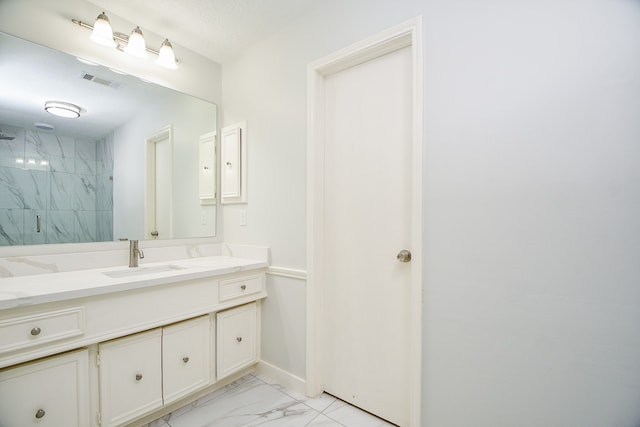 bathroom featuring tiled shower and vanity