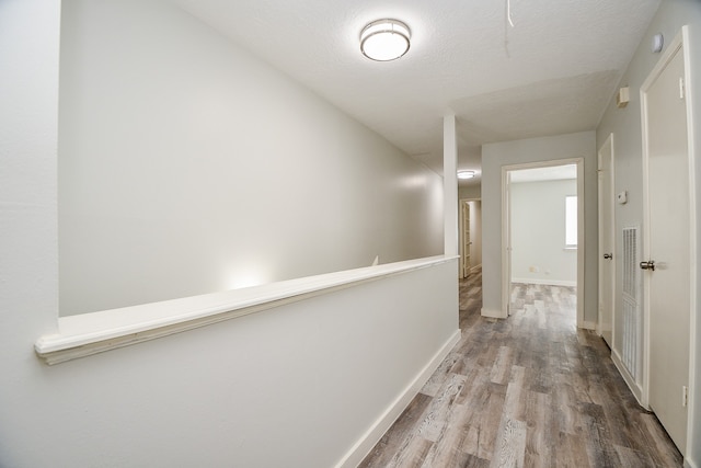 corridor with hardwood / wood-style floors and a textured ceiling