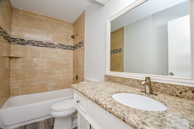 full bathroom with vanity, a textured ceiling, tiled shower / bath combo, wood-type flooring, and toilet